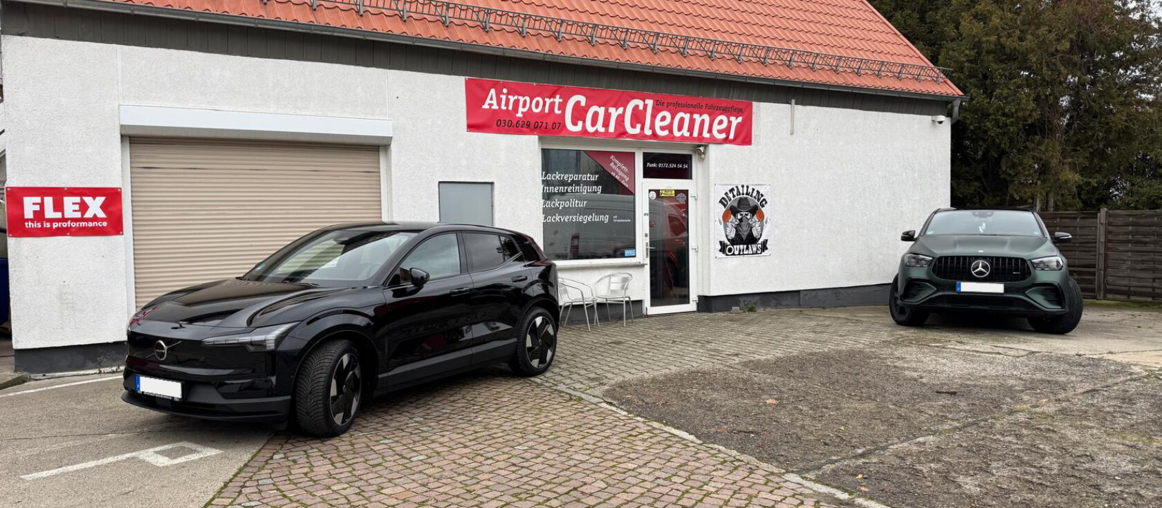 Betriebsgebäude von Airport CarCleaner in Schönefeld mit zwei frisch aufbereiteten schwarzen Fahrzeugen davor